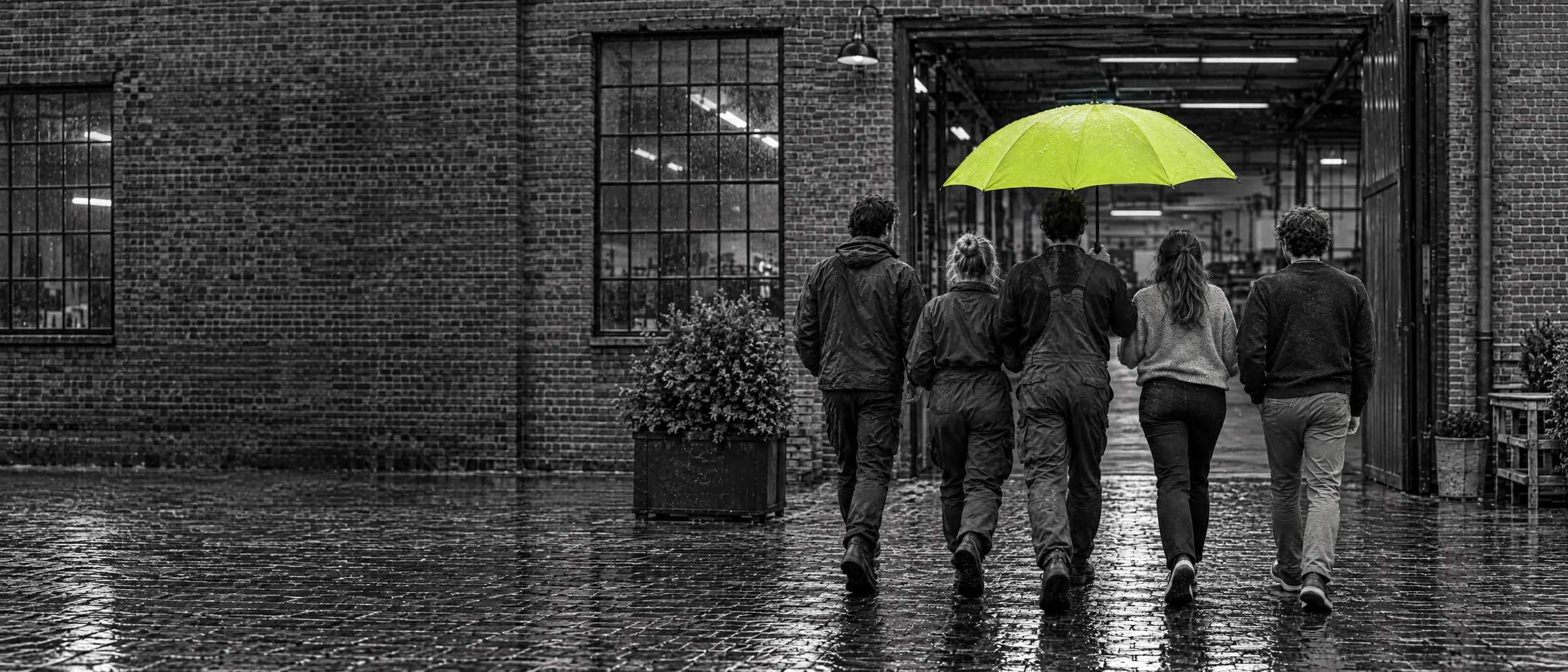 Vijf medewerkers lopen samen onder een lime paraplu een werkplaats binnen