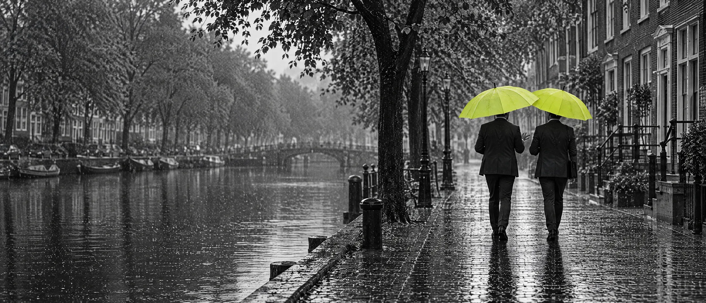 Twee mannen in pak lopen naast elkaar langs een gracht, elk met een lime paraplu